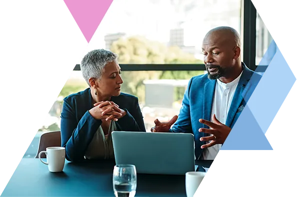 Business professionals sitting at a desk in front of a laptop and talking
